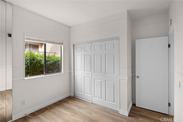 unfurnished bedroom with light wood-type flooring and a closet