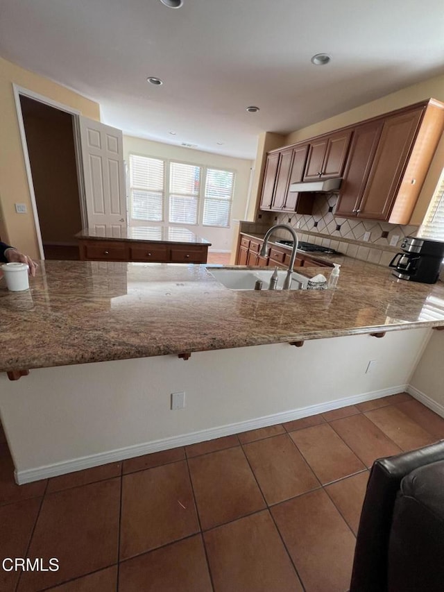 kitchen featuring tasteful backsplash, sink, tile patterned flooring, and light stone counters