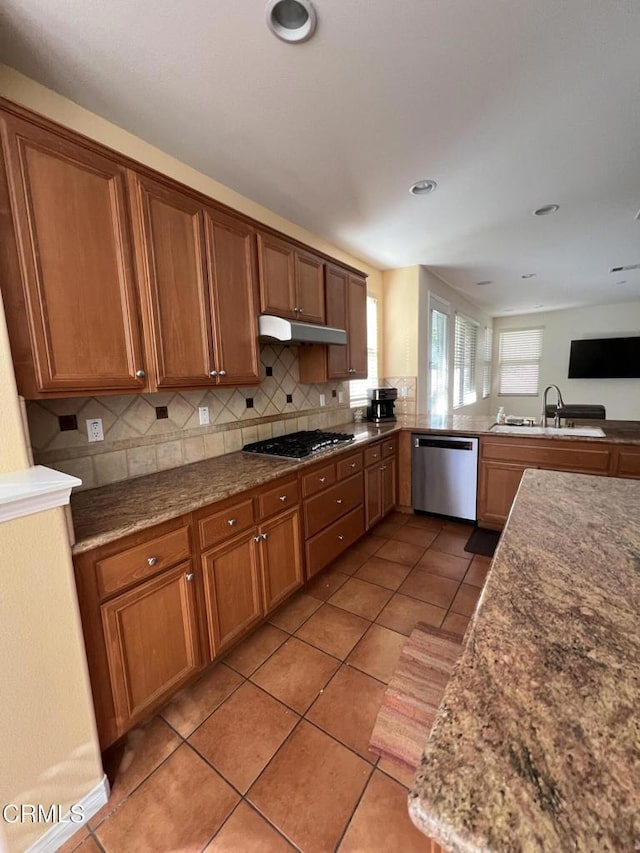 kitchen with sink, tile patterned flooring, stainless steel appliances, decorative backsplash, and kitchen peninsula