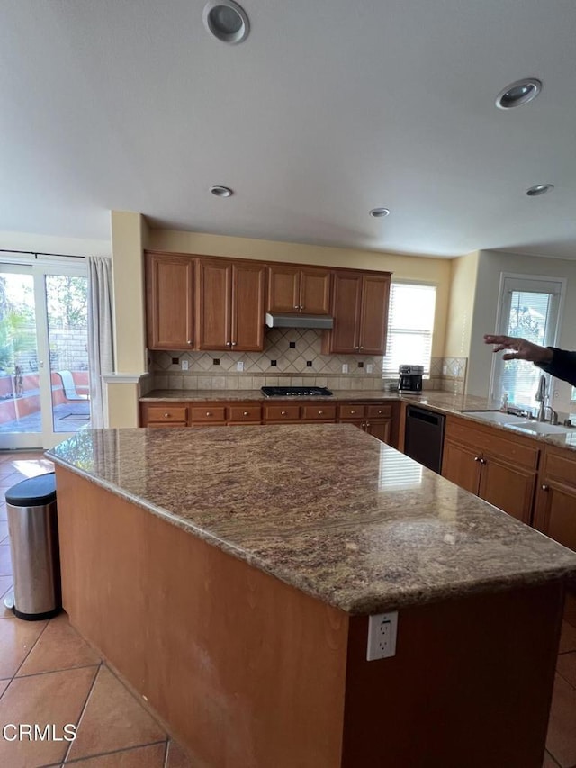 kitchen featuring a kitchen island, stone countertops, tasteful backsplash, dishwasher, and stainless steel gas cooktop