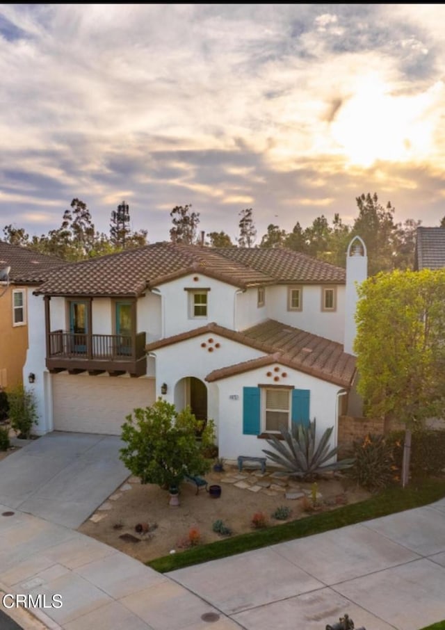 mediterranean / spanish house featuring a garage, driveway, a tiled roof, and stucco siding