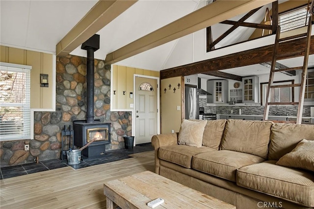 living room featuring wood-type flooring, lofted ceiling with beams, and a wood stove