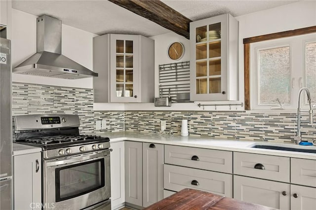 kitchen featuring light countertops, wall chimney exhaust hood, and stainless steel gas range oven