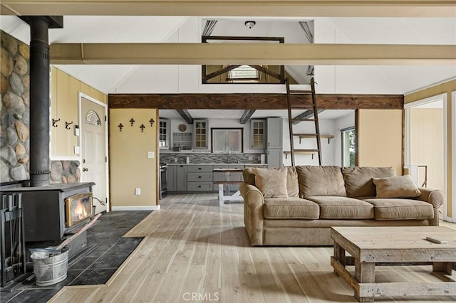 living room with vaulted ceiling with beams, hardwood / wood-style flooring, and a wood stove