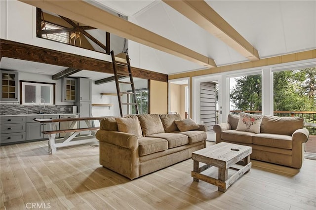 living room featuring vaulted ceiling with beams, sink, and light wood-type flooring