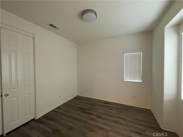 unfurnished bedroom with baseboards, visible vents, and dark wood-type flooring