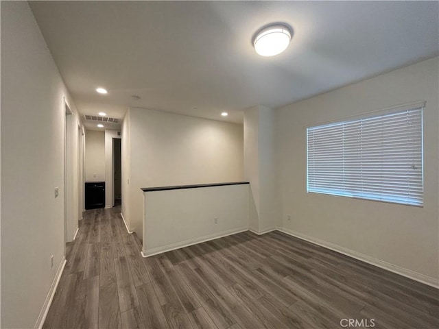 spare room with recessed lighting, wood finished floors, visible vents, and baseboards