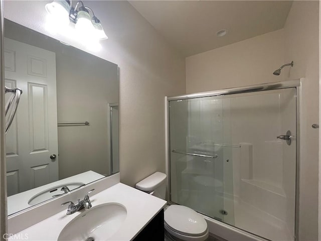 bathroom featuring toilet, a shower stall, and vanity