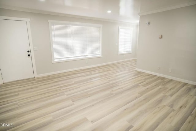 spare room featuring crown molding and light hardwood / wood-style floors