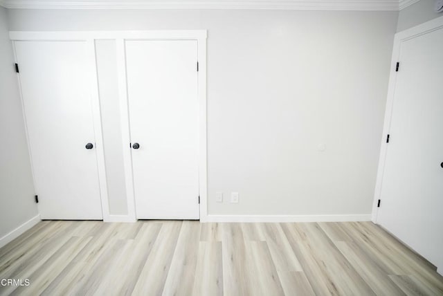 unfurnished bedroom featuring light wood-type flooring, a closet, and crown molding