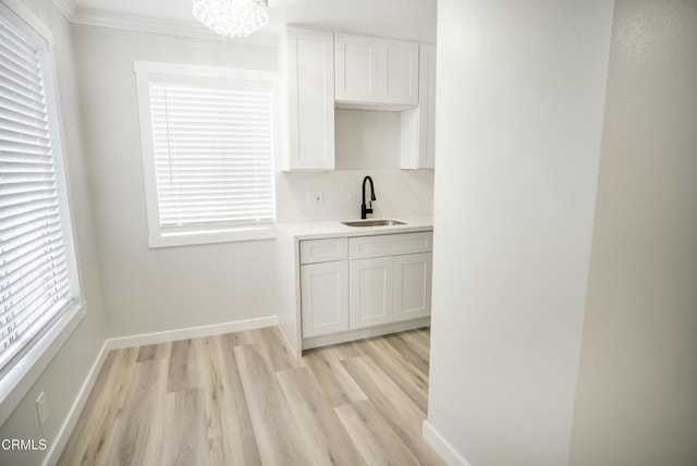 kitchen with sink, white cabinetry, a notable chandelier, and light hardwood / wood-style flooring