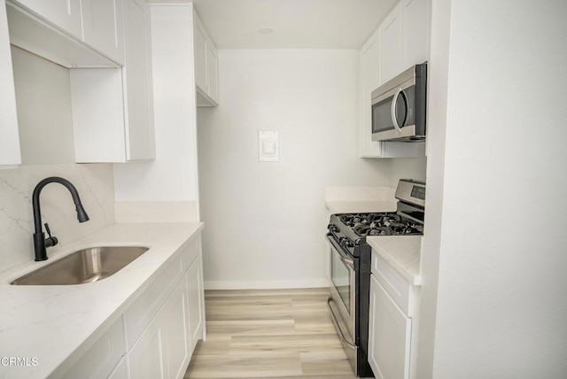 kitchen featuring sink, white cabinets, stainless steel appliances, and light stone counters