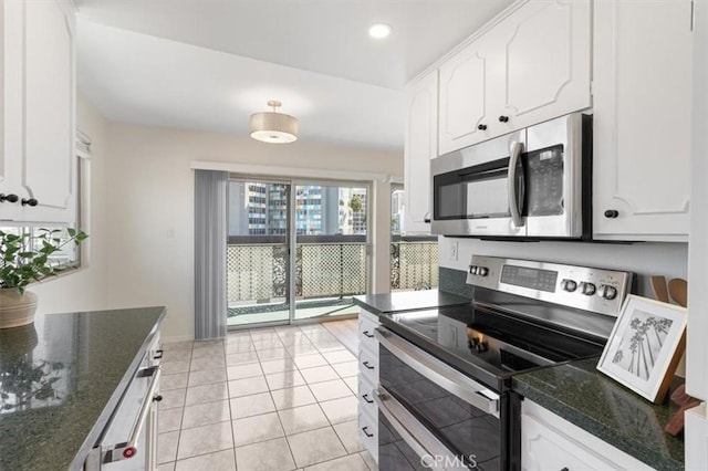 kitchen featuring dark stone counters, white cabinetry, stainless steel appliances, and baseboards