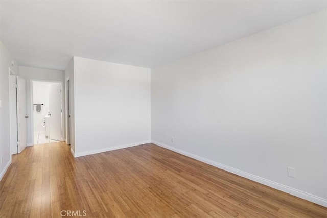 spare room with baseboards and light wood-style floors