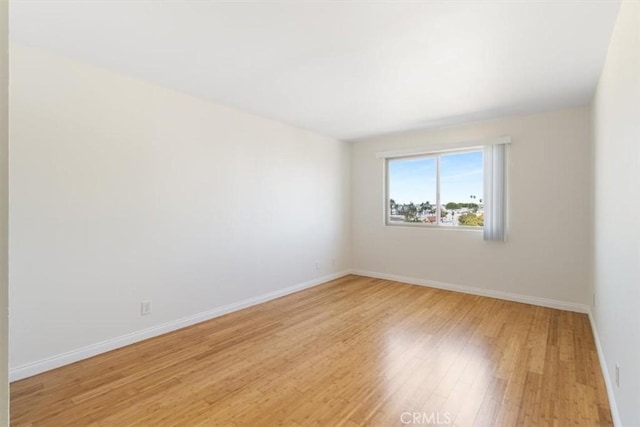 empty room featuring baseboards and light wood-type flooring