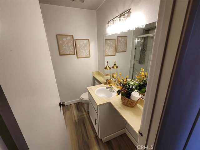 bathroom with wood-type flooring, toilet, an enclosed shower, and vanity