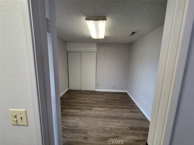 empty room featuring dark wood-type flooring and a textured ceiling