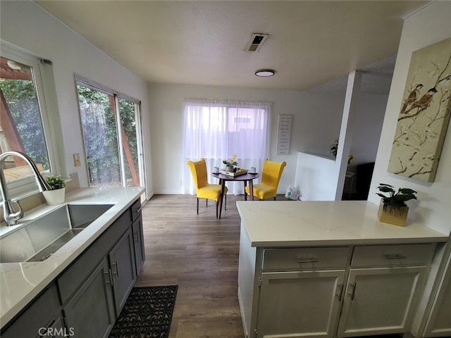 kitchen featuring light stone counters, sink, gray cabinets, and dark hardwood / wood-style floors