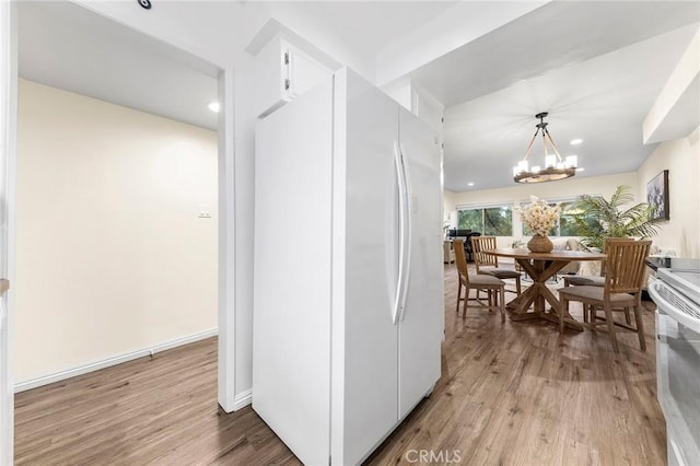 kitchen with white cabinetry, hanging light fixtures, light hardwood / wood-style flooring, and white fridge