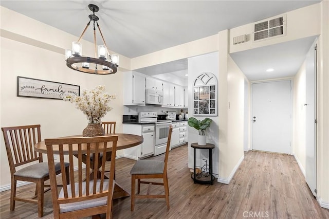 dining space with a notable chandelier and light hardwood / wood-style floors