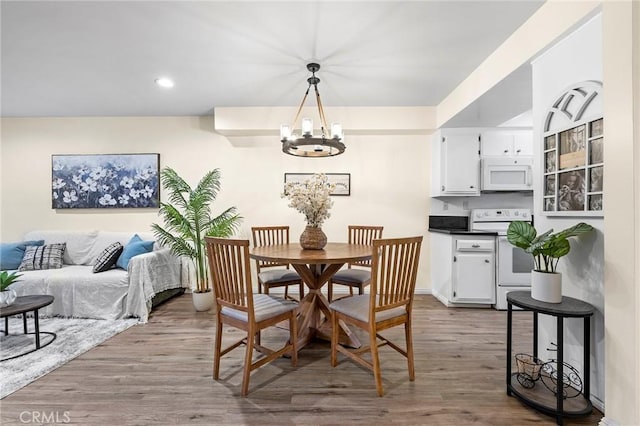 dining space with hardwood / wood-style flooring and an inviting chandelier