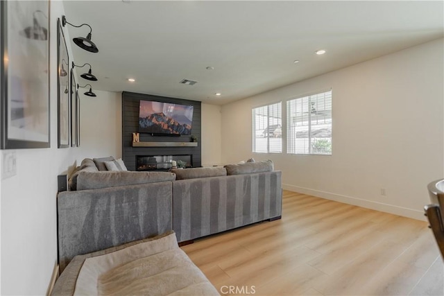 living room with recessed lighting, a fireplace, light wood-style flooring, and baseboards