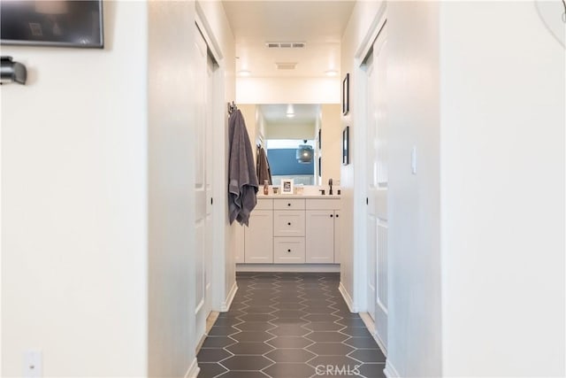 hallway featuring dark tile patterned floors, a sink, and visible vents