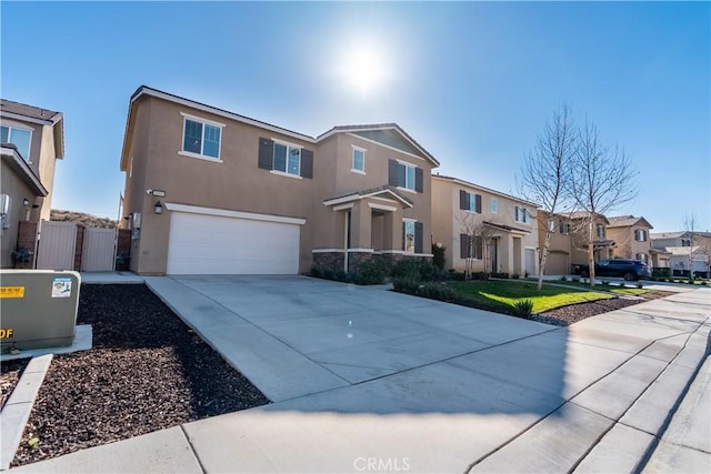 view of front of home with concrete driveway, a residential view, an attached garage, fence, and stucco siding