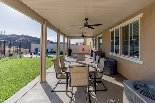 view of patio / terrace featuring ceiling fan, outdoor dining area, cooling unit, a mountain view, and a fenced backyard