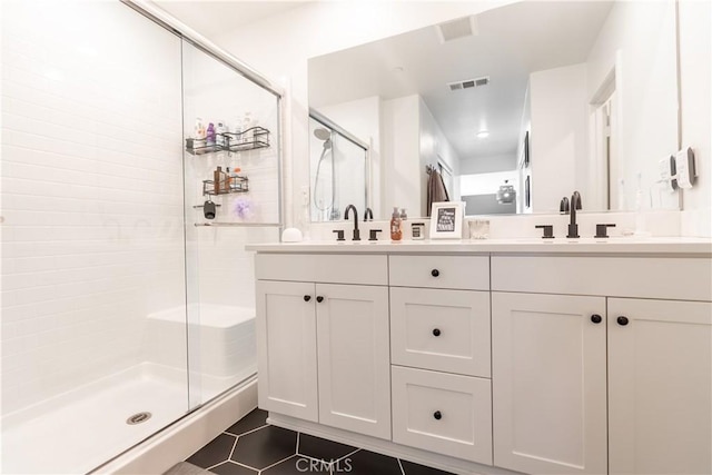 bathroom featuring double vanity, visible vents, a sink, a shower stall, and tile patterned floors