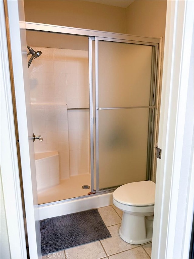 bathroom featuring a shower stall, toilet, and tile patterned floors