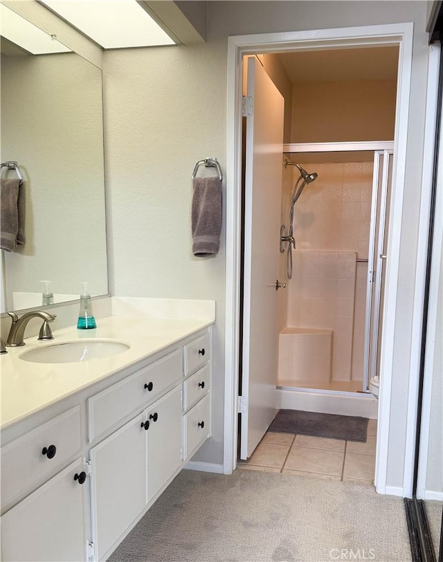 bathroom with a shower stall, tile patterned flooring, and vanity