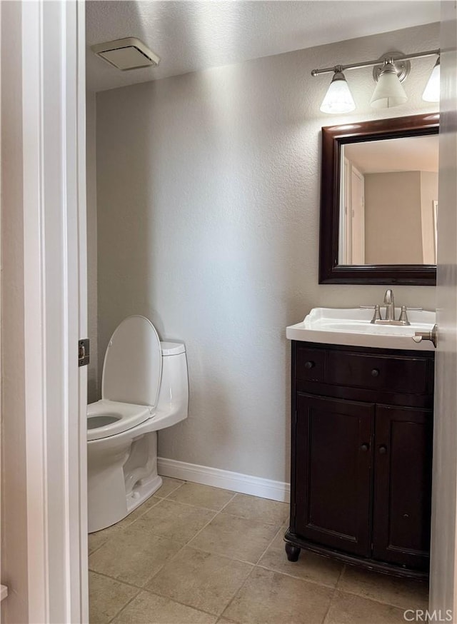 half bath with tile patterned flooring, vanity, toilet, and baseboards