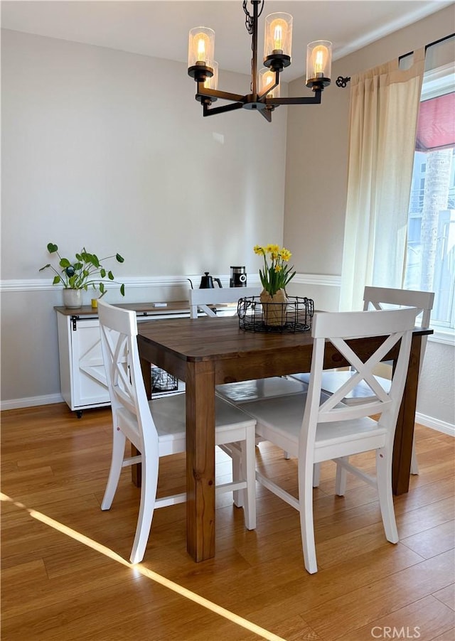 dining area with light wood-style floors, a notable chandelier, and baseboards