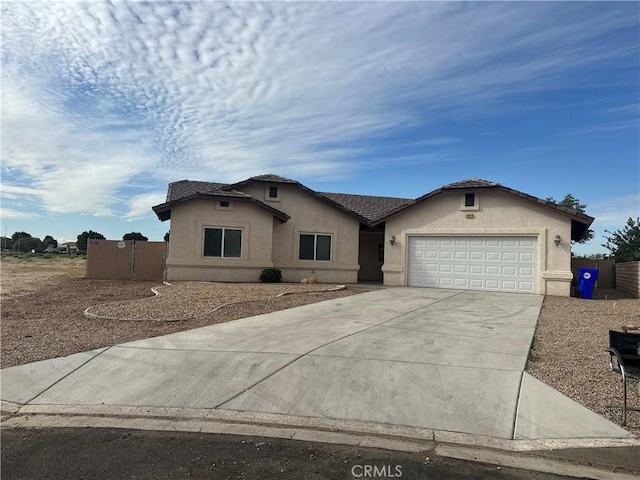 ranch-style house featuring driveway, an attached garage, fence, and stucco siding