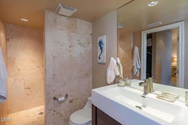 bathroom featuring walk in shower, vanity, and toilet