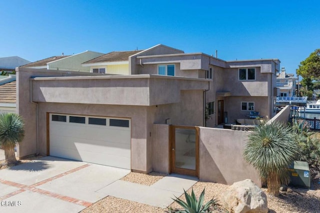 view of front facade with a garage, concrete driveway, fence, and stucco siding