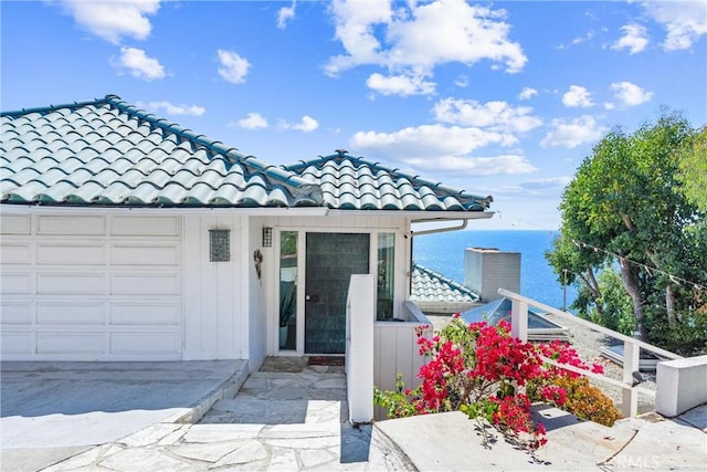 view of front facade with an attached garage, a water view, and a tile roof