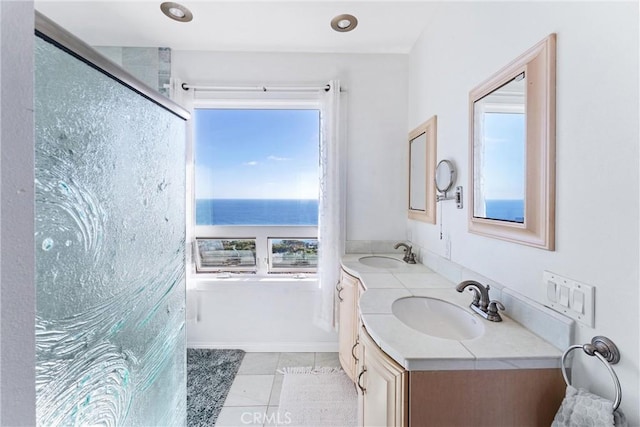 bathroom featuring a water view, a sink, a shower stall, and double vanity