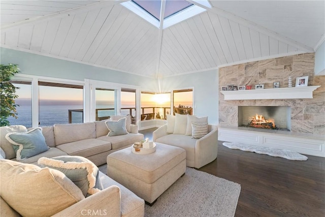 living room with dark wood-type flooring, a skylight, high vaulted ceiling, a water view, and a fireplace