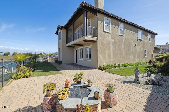 back of house featuring a balcony, a yard, and a patio area