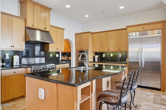 kitchen with stainless steel appliances, sink, a center island with sink, and dark stone counters