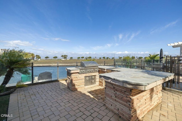 view of patio with a water view, an outdoor kitchen, a bar, and area for grilling