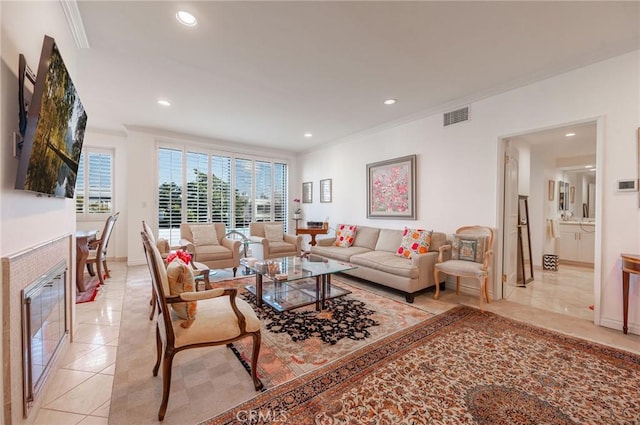 living area with recessed lighting, visible vents, ornamental molding, a glass covered fireplace, and light tile patterned flooring