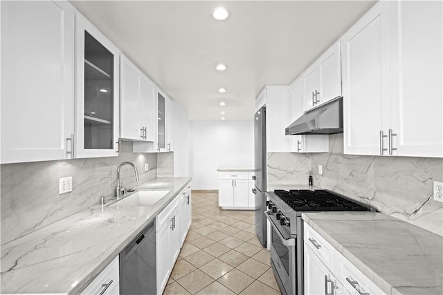 kitchen with under cabinet range hood, stainless steel appliances, white cabinetry, and a sink