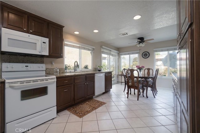 kitchen with dark brown cabinetry, sink, white appliances, and light tile patterned floors