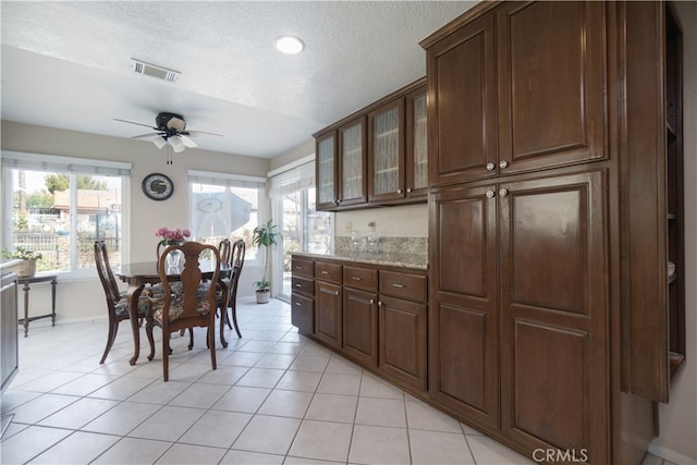 dining room with light tile patterned flooring, ceiling fan, and a textured ceiling