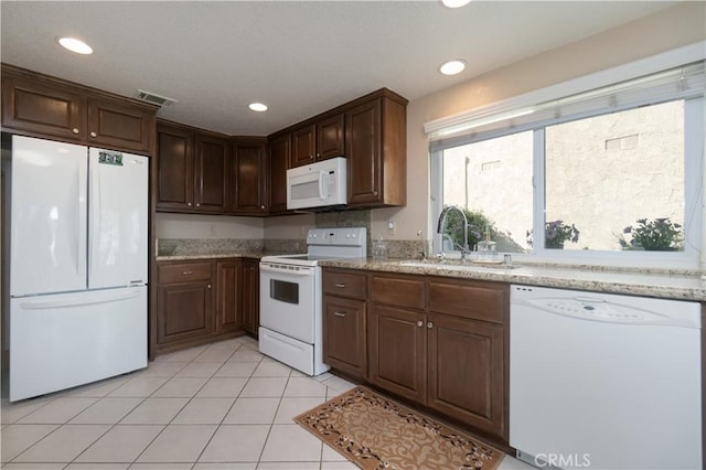 kitchen with light stone counters, white appliances, sink, and light tile patterned floors