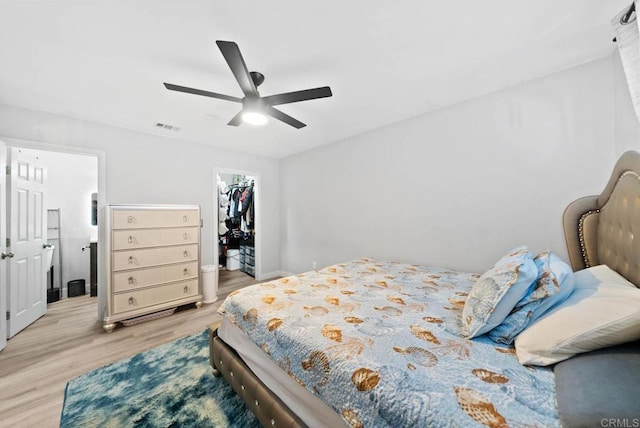 bedroom featuring ceiling fan, a walk in closet, a closet, and light hardwood / wood-style flooring