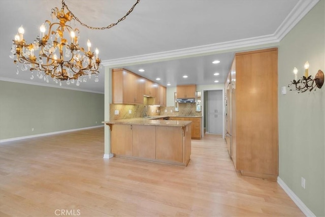 32709 Seagate Dr Unit 101, Rancho Palos Verdes, CA 90275 - kitchen with crown molding, a chandelier, a peninsula, under cabinet range hood, and light wood-style flooring